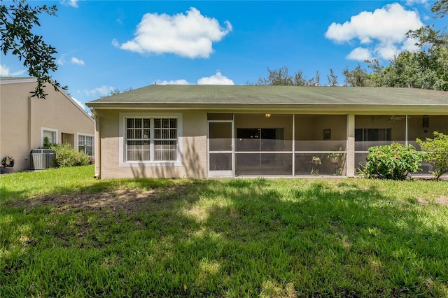 rear view of property featuring a lawn and central air condition unit