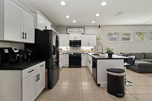 kitchen featuring white cabinetry, sink, a kitchen bar, light tile patterned floors, and black appliances