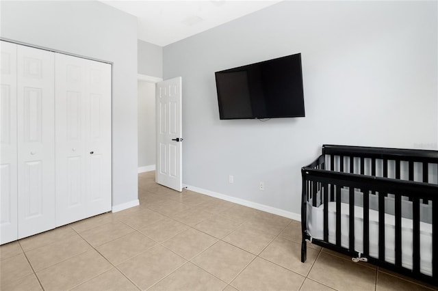 bedroom with light tile patterned flooring, a crib, and a closet