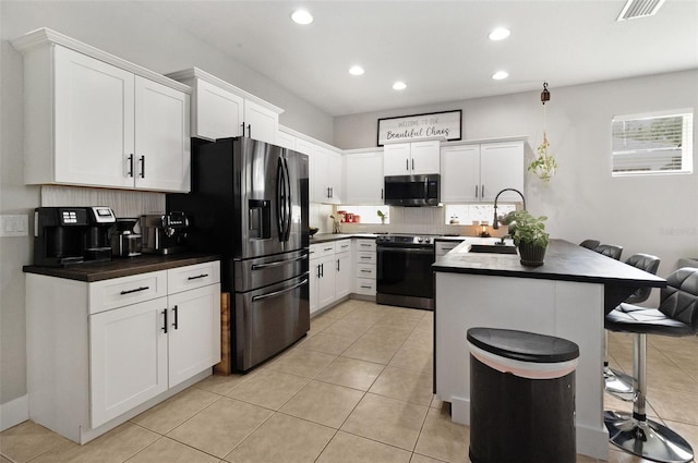 kitchen with white cabinets, a kitchen island, stainless steel appliances, and a breakfast bar area