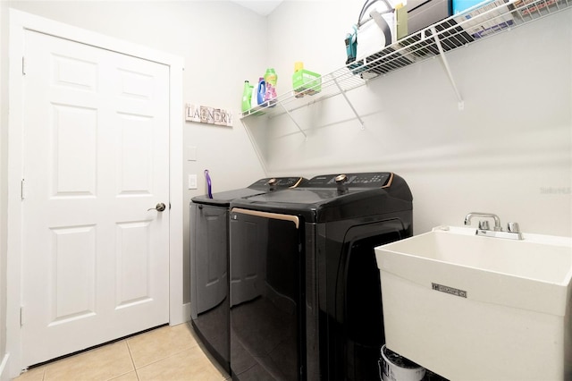 clothes washing area with independent washer and dryer, sink, and light tile patterned floors