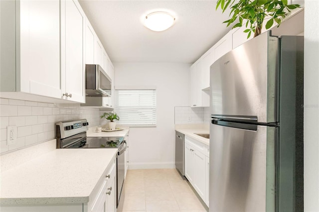 kitchen featuring white cabinetry, light tile patterned flooring, appliances with stainless steel finishes, and tasteful backsplash