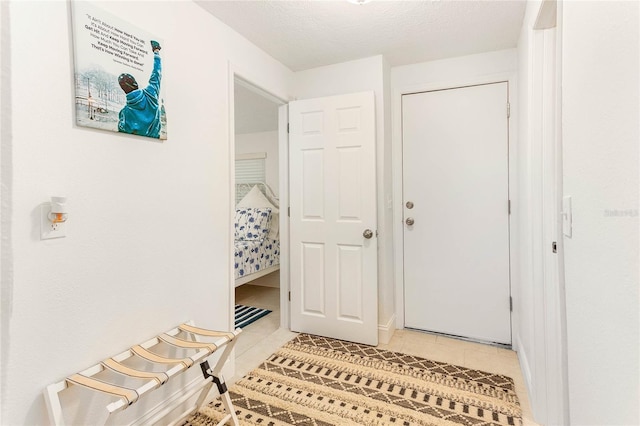 corridor with a textured ceiling and light tile patterned floors