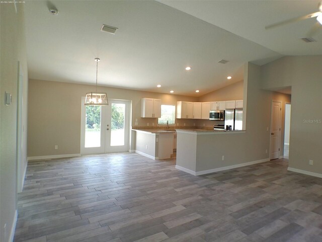 kitchen with decorative light fixtures, hardwood / wood-style floors, stainless steel appliances, sink, and white cabinets