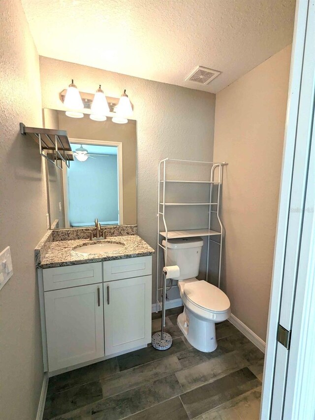 bathroom featuring a textured ceiling, vanity, toilet, and hardwood / wood-style floors