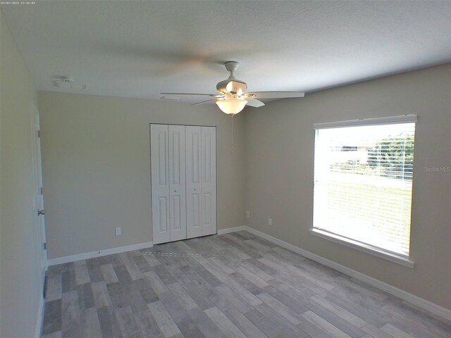 unfurnished bedroom with wood-type flooring, ceiling fan, and a closet