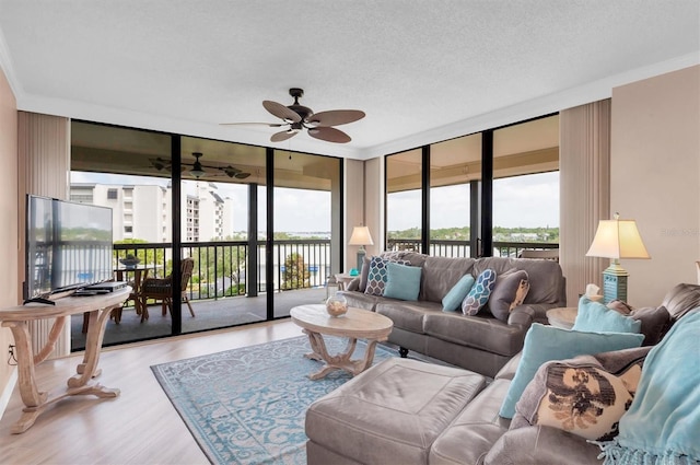 living room featuring ceiling fan, expansive windows, a textured ceiling, and light hardwood / wood-style flooring