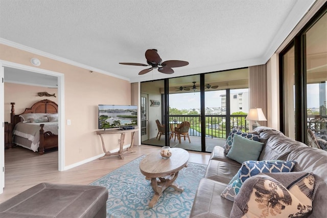 living room with light wood-type flooring, ceiling fan, crown molding, and a textured ceiling