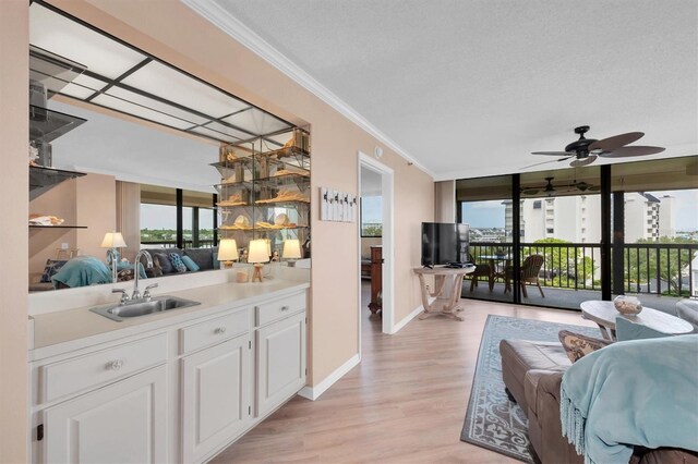 bar featuring white cabinets, light wood-type flooring, sink, ceiling fan, and ornamental molding