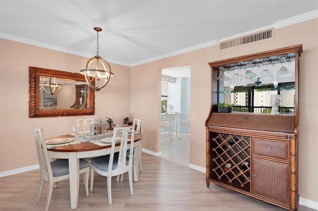 dining area featuring ornamental molding, a textured ceiling, wood-type flooring, and a notable chandelier