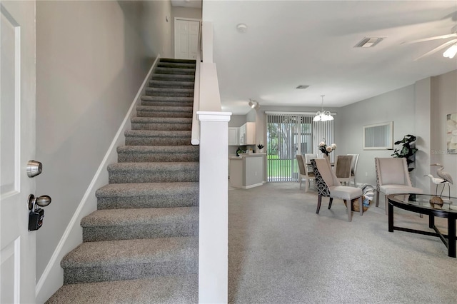 stairs featuring a chandelier