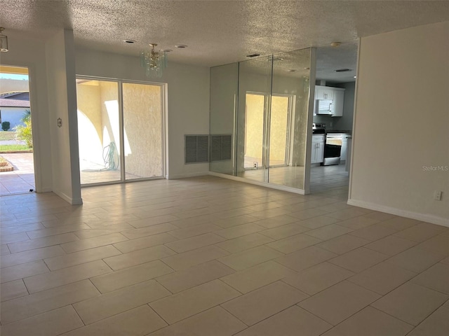 unfurnished room featuring a textured ceiling, an inviting chandelier, and tile patterned flooring