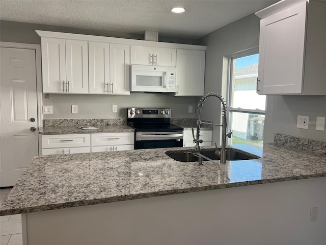 kitchen featuring stainless steel range with electric stovetop, light stone counters, sink, and white cabinets