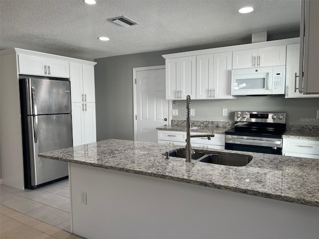 kitchen featuring stone counters, white cabinetry, a textured ceiling, stainless steel appliances, and sink