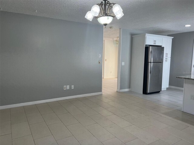 interior space with a textured ceiling, light tile patterned flooring, and a notable chandelier