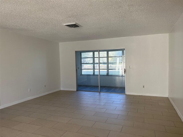 empty room with tile patterned flooring and a textured ceiling