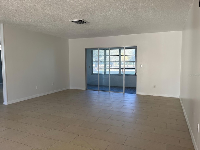 tiled spare room with a textured ceiling