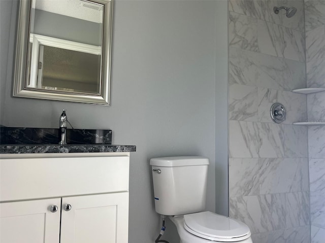 bathroom featuring vanity, toilet, and a tile shower