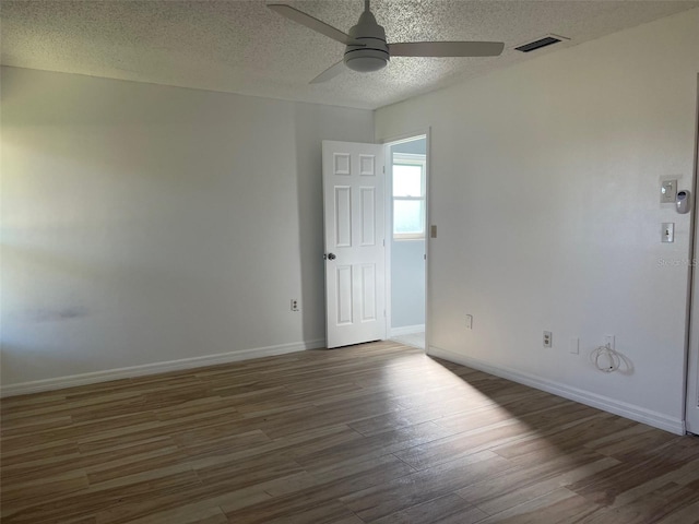 unfurnished room with dark wood-type flooring, ceiling fan, and a textured ceiling