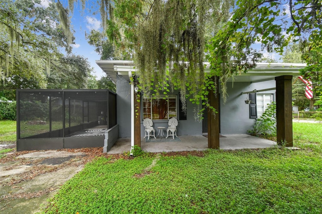 back of property with a sunroom, a yard, and a patio area