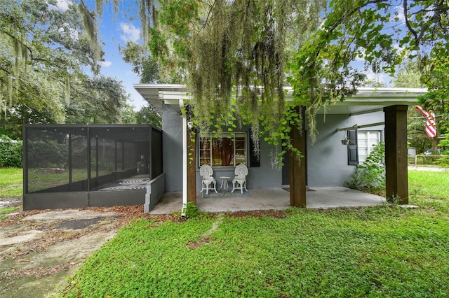 back of property with a sunroom, a yard, and a patio area