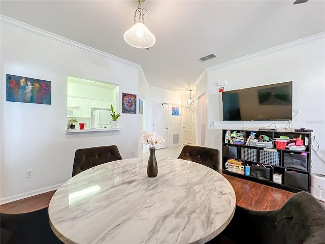 dining space featuring ornamental molding and hardwood / wood-style floors