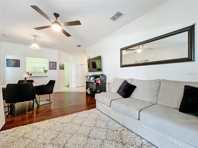 living room featuring ornamental molding, ceiling fan, and dark wood-type flooring