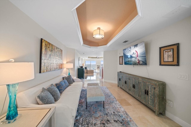 living room with a tray ceiling and baseboards