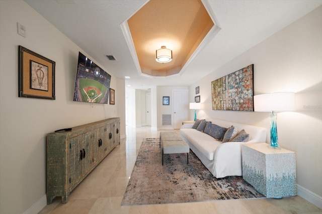 living room with a raised ceiling, visible vents, and baseboards