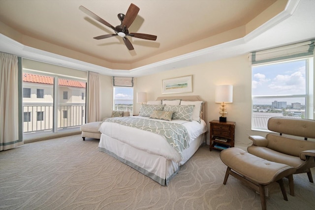 bedroom with ceiling fan, access to outside, carpet flooring, and a raised ceiling