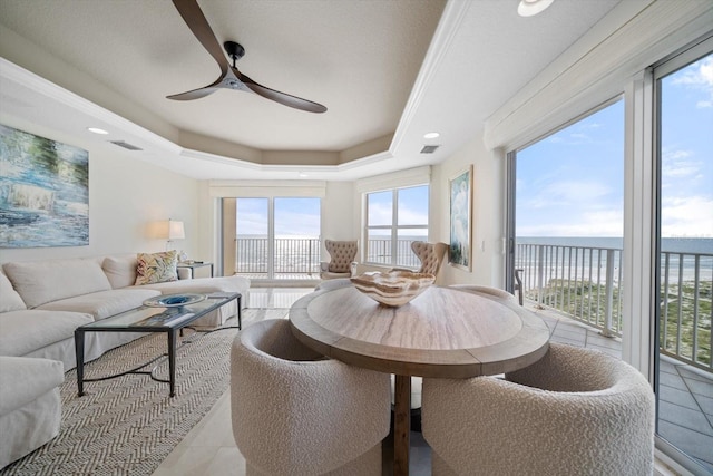 sunroom featuring a tray ceiling, visible vents, and ceiling fan