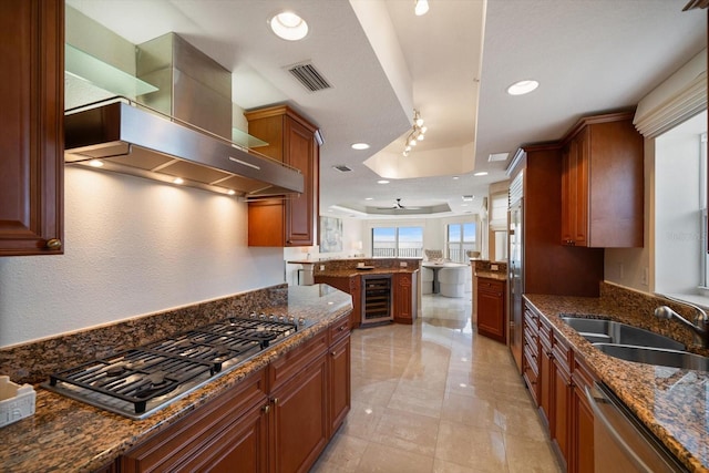 kitchen with wine cooler, stainless steel appliances, visible vents, a sink, and wall chimney range hood