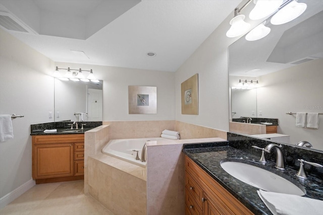 bathroom featuring a bath, visible vents, two vanities, and a sink