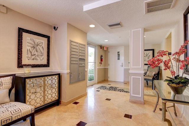 entrance foyer with baseboards, mail area, visible vents, and a textured ceiling