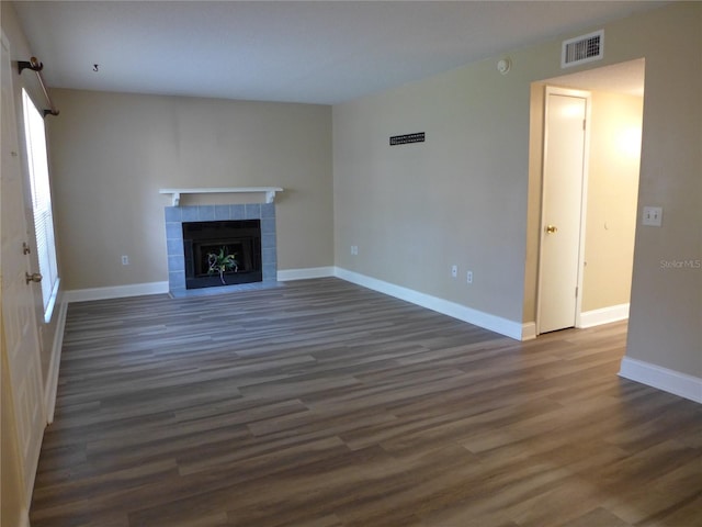 unfurnished living room with dark hardwood / wood-style floors and a tile fireplace