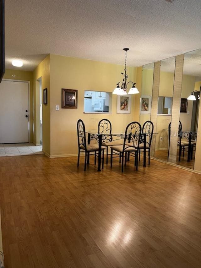 dining room featuring a chandelier, wood-type flooring, and a textured ceiling