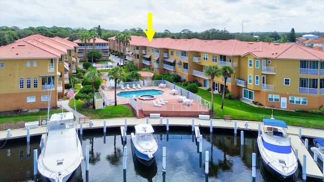 view of dock featuring a community pool, a water view, a patio area, and a balcony