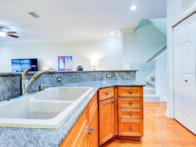 kitchen featuring light stone countertops, light hardwood / wood-style floors, sink, ceiling fan, and ornamental molding