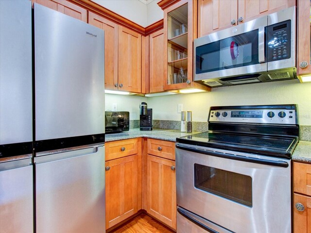 kitchen featuring appliances with stainless steel finishes, light hardwood / wood-style flooring, and light stone countertops