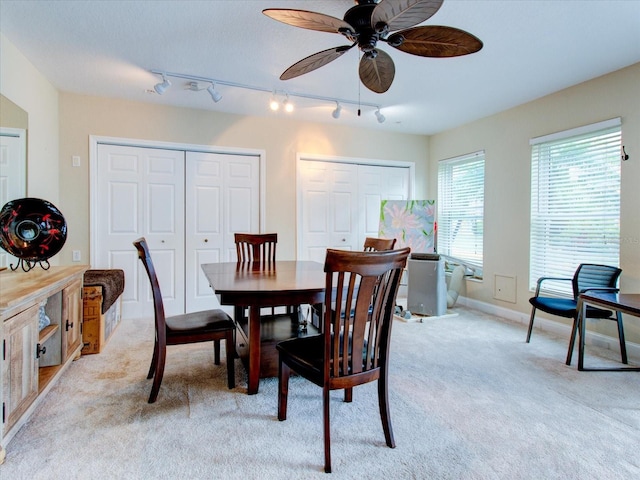 dining space featuring track lighting, ceiling fan, and light carpet