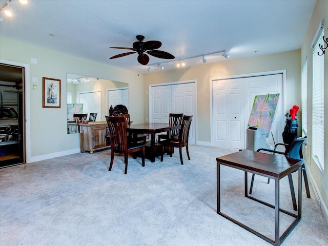 dining area featuring rail lighting, ceiling fan, plenty of natural light, and light carpet