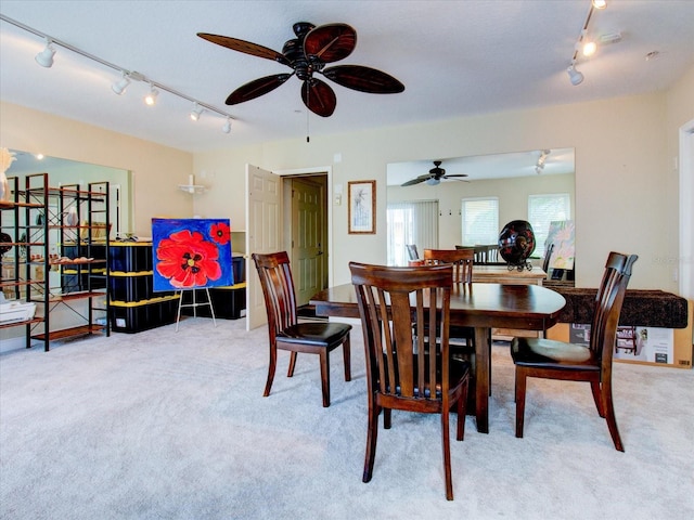 carpeted dining space with rail lighting and ceiling fan