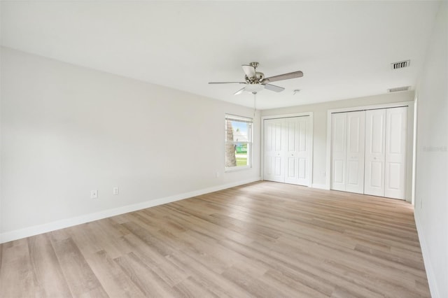 unfurnished bedroom with two closets, ceiling fan, and light wood-type flooring