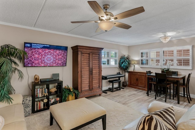 living area with light wood-style flooring, a textured ceiling, a ceiling fan, and ornamental molding