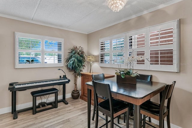 dining area with a textured ceiling, wood finished floors, crown molding, baseboards, and a chandelier