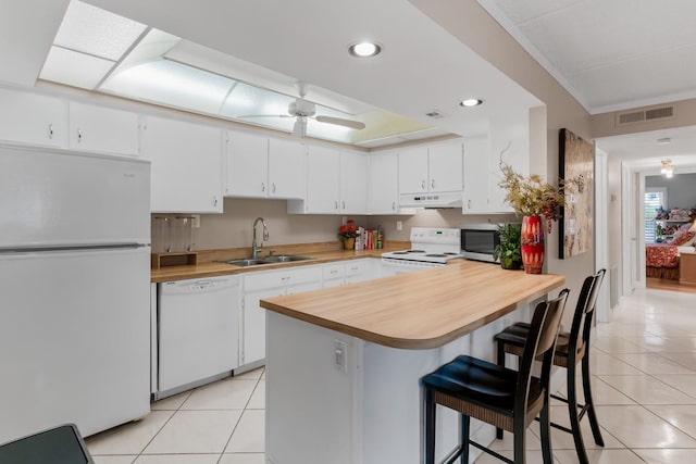 kitchen with visible vents, under cabinet range hood, light tile patterned flooring, white appliances, and a sink