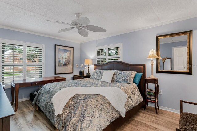 bedroom with baseboards, multiple windows, a textured ceiling, and wood finished floors