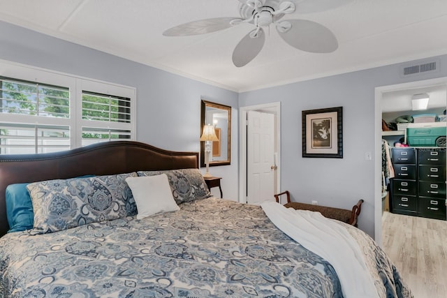 bedroom featuring ceiling fan, visible vents, wood finished floors, and ornamental molding