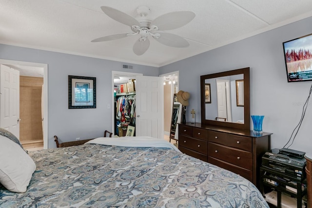 bedroom with a spacious closet, visible vents, ceiling fan, a closet, and ensuite bath