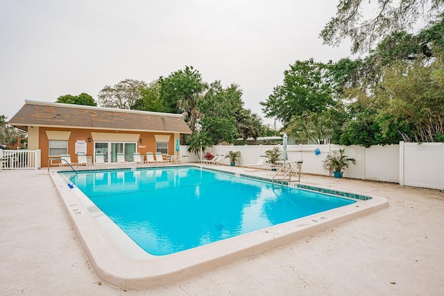 community pool with a patio area and a fenced backyard